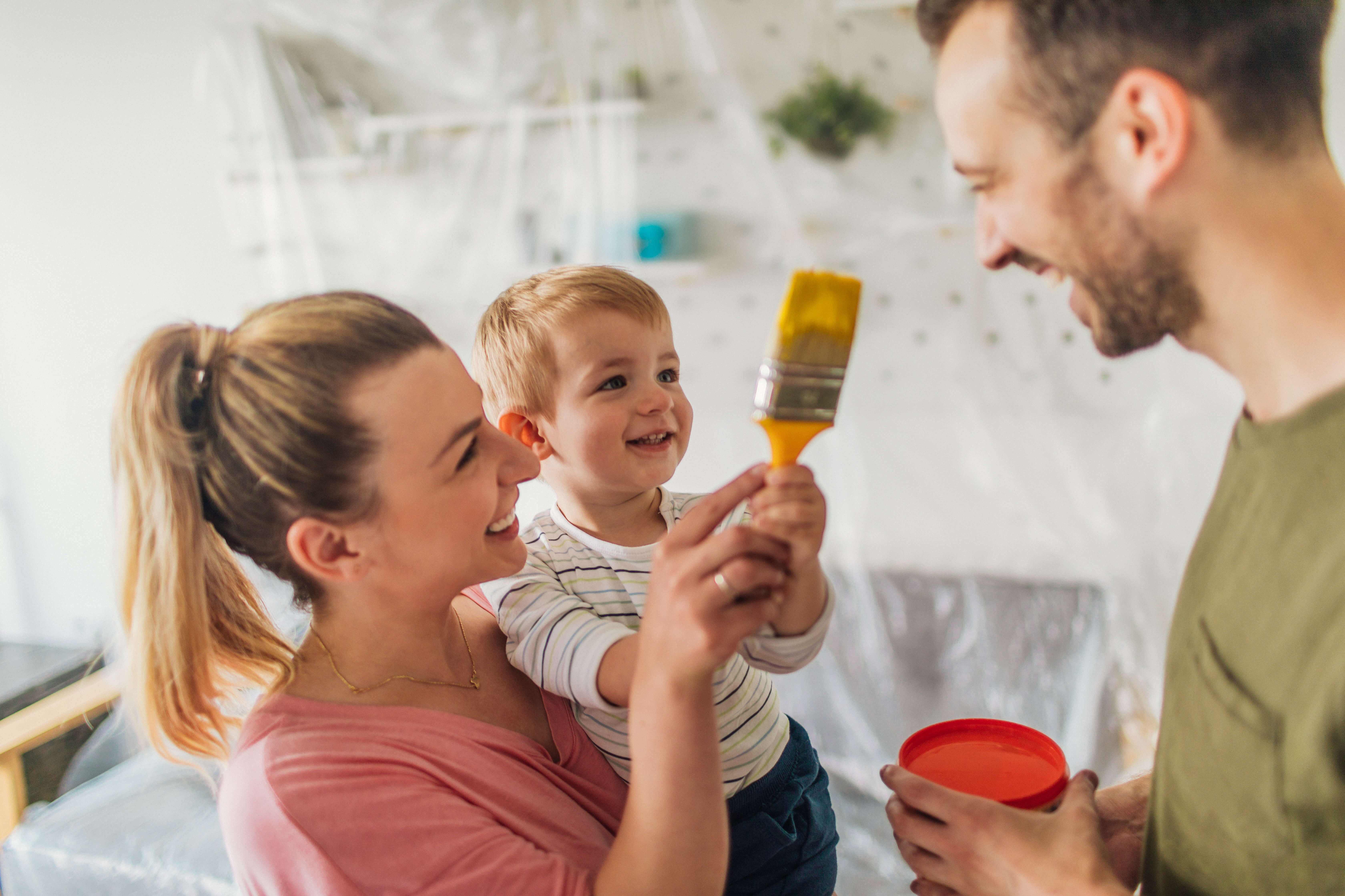 Couple with a baby holding a paint brush