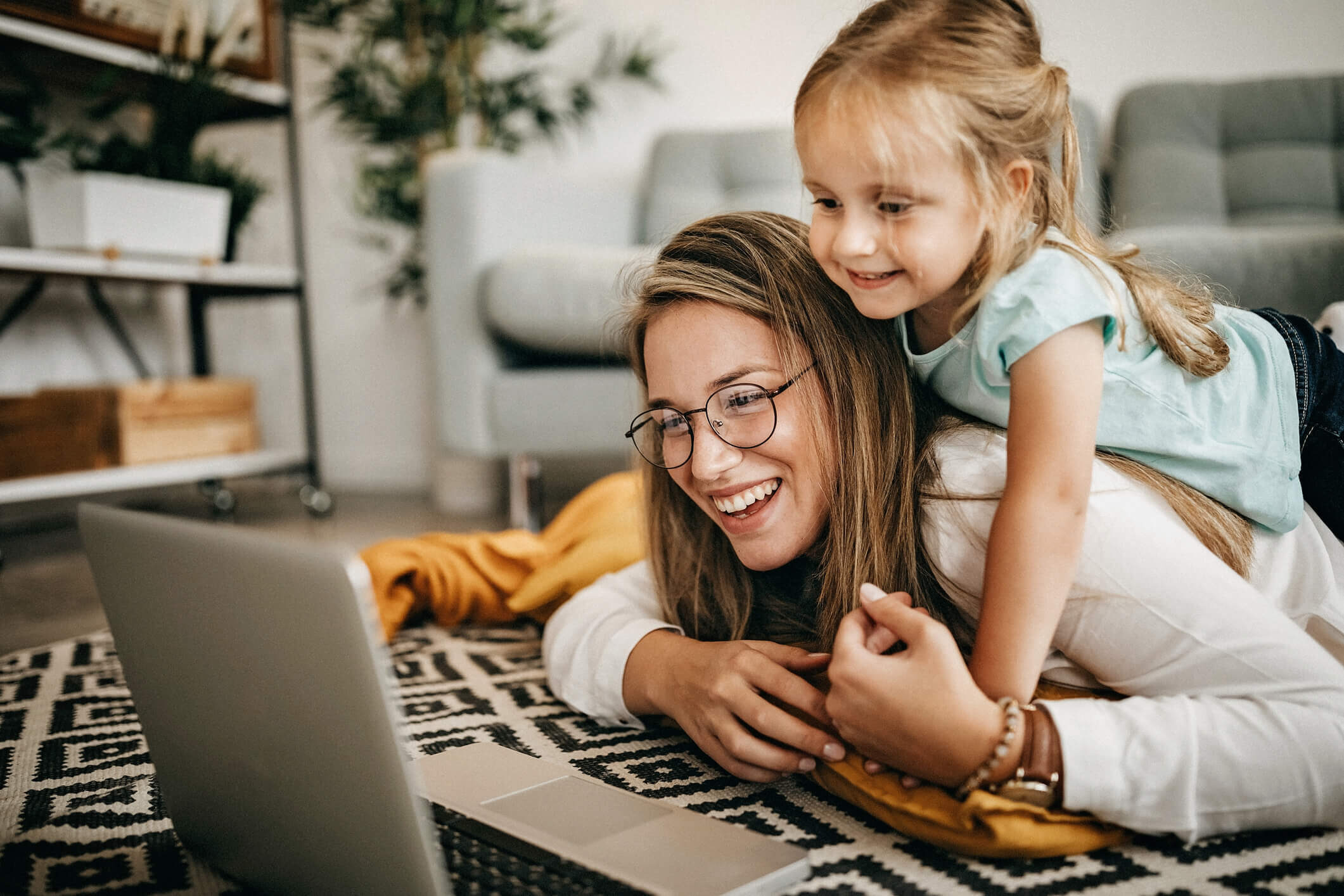 Mom and daughter laying on the floor and looking at computer