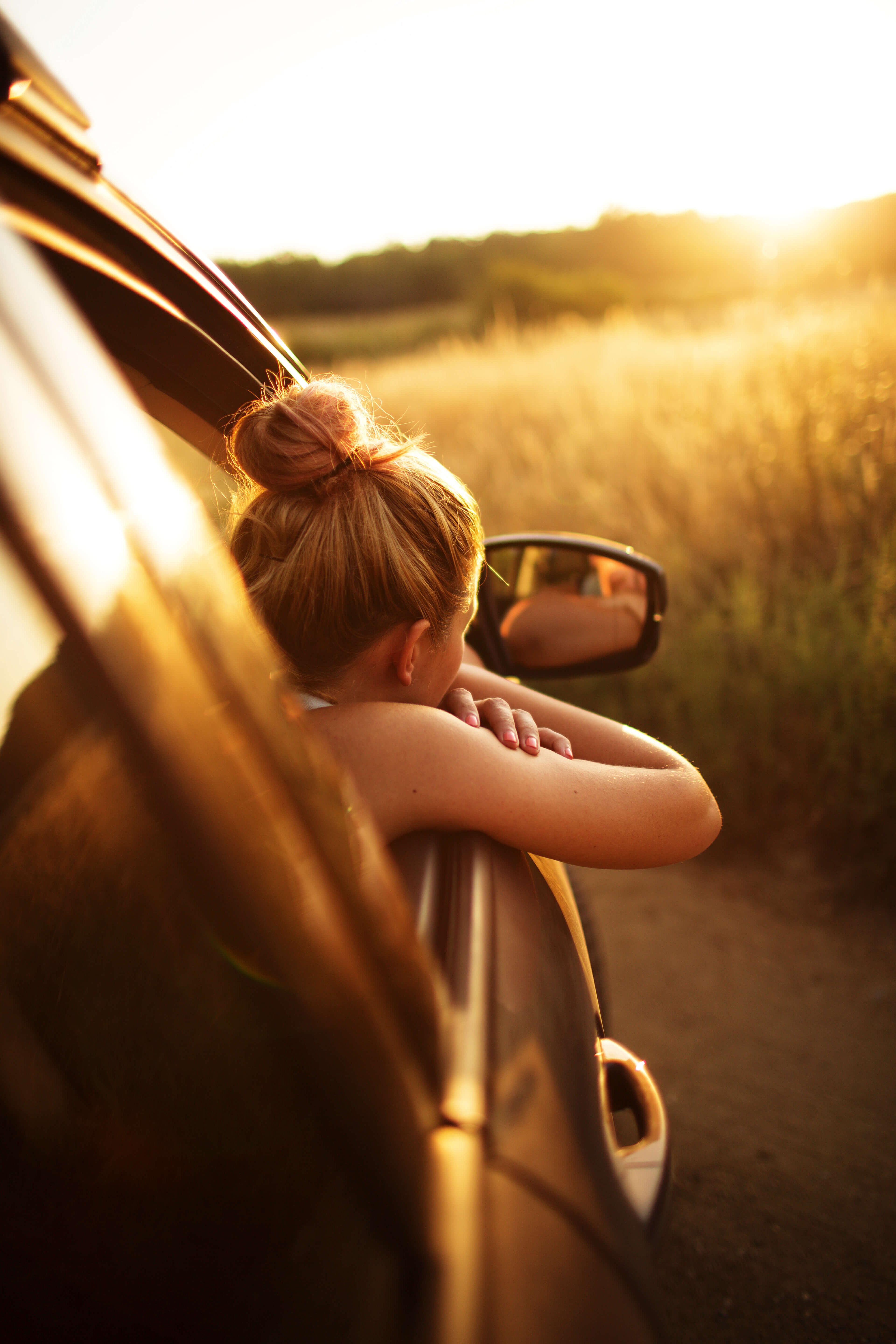 Woman enjoying car ride and sunset