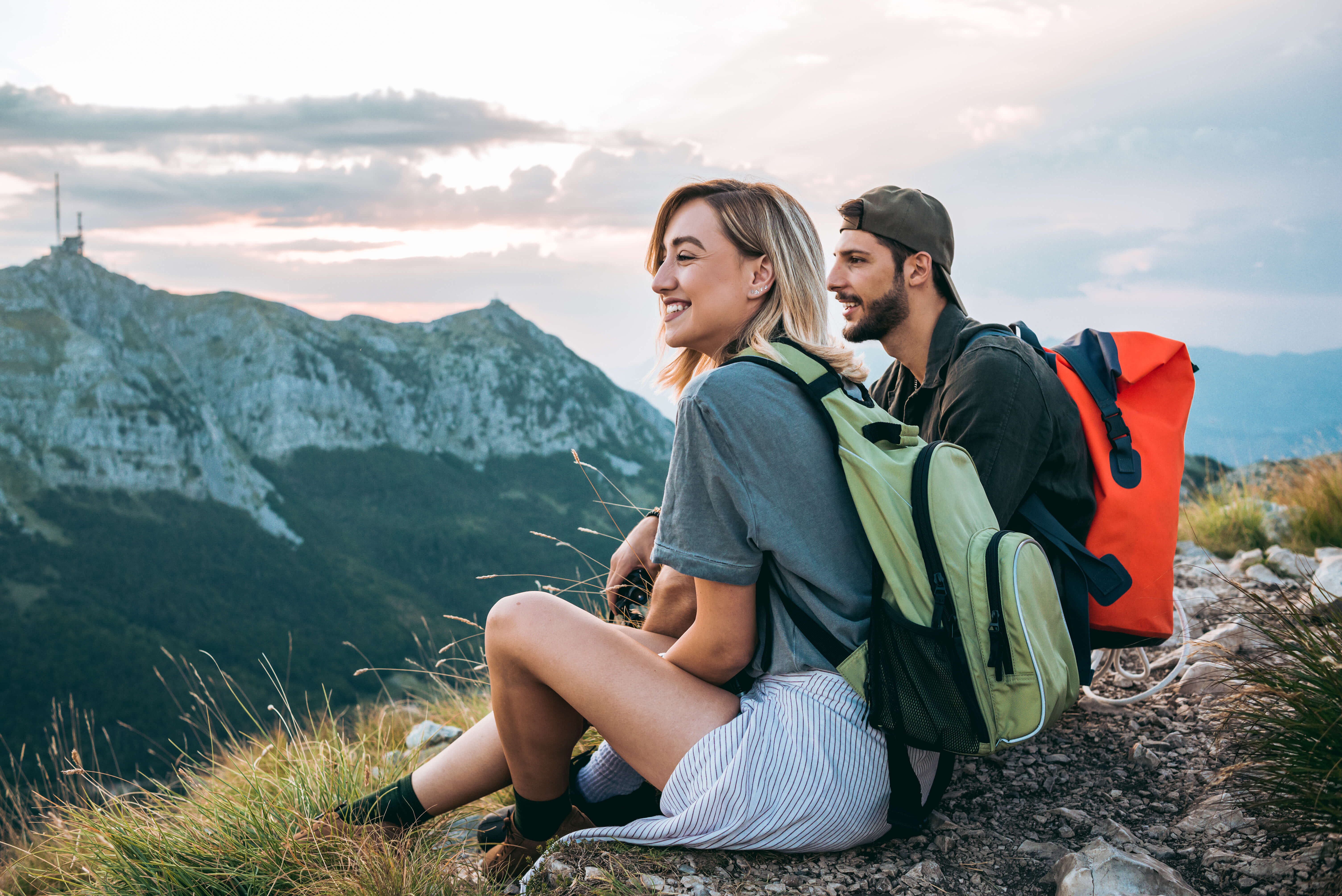 Young couple sitting on top of a mountain on a hike