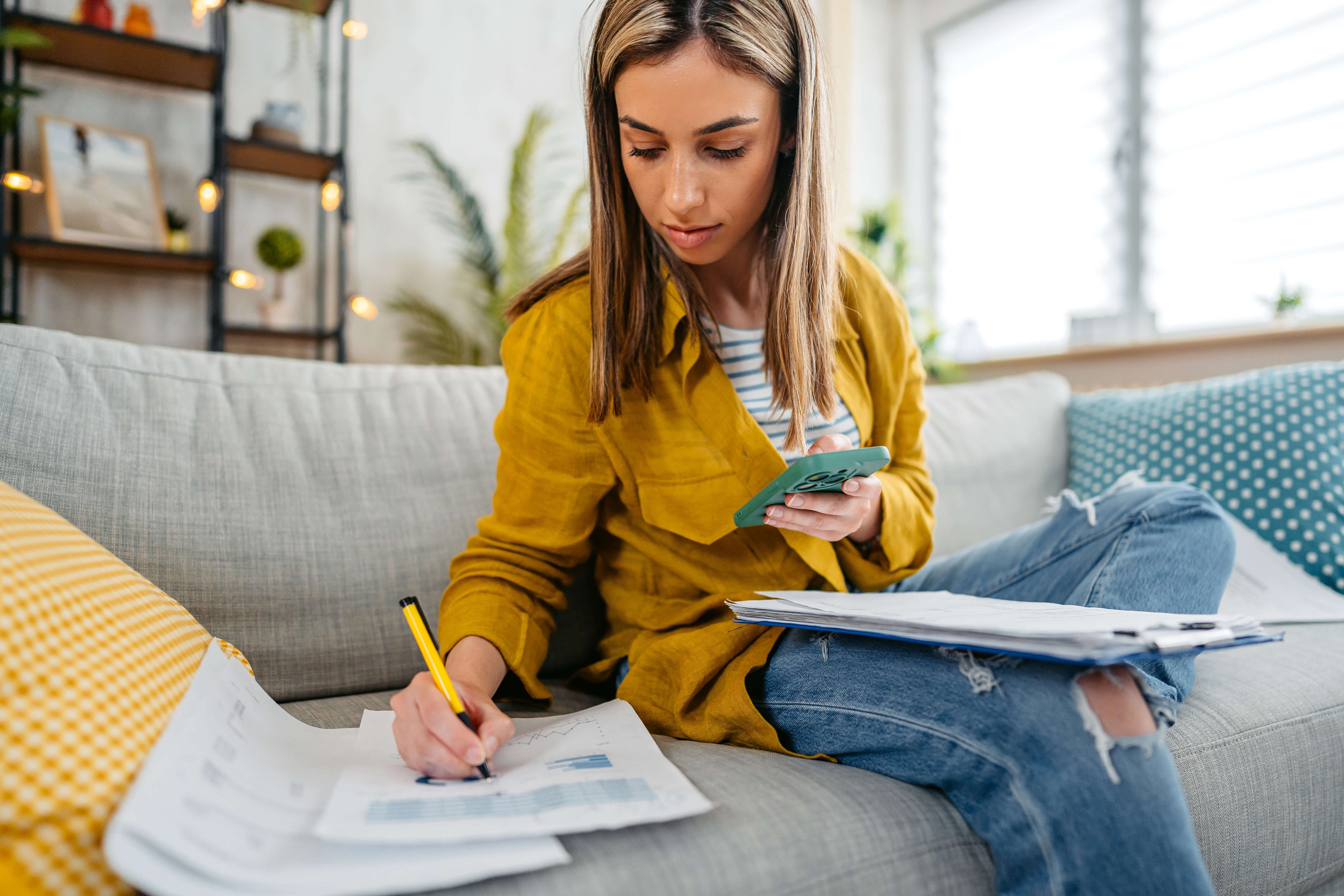 Young woman sitting on couch and writing her budget