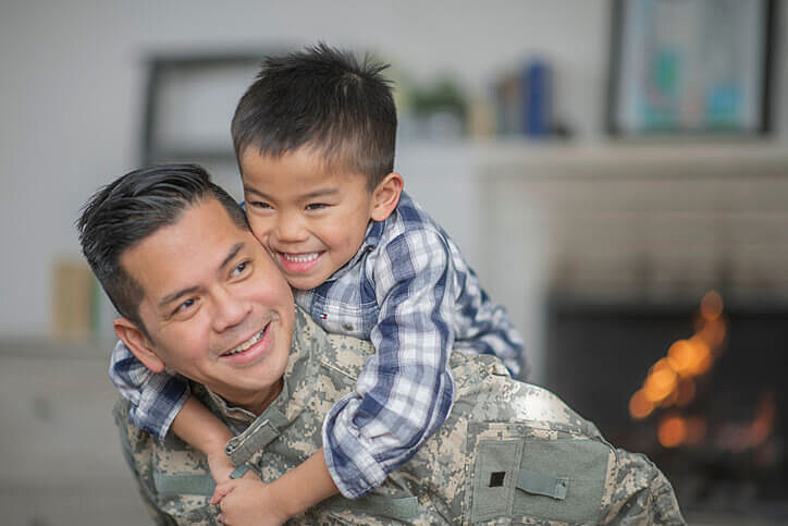 Young child holding his military dad arriving home 1